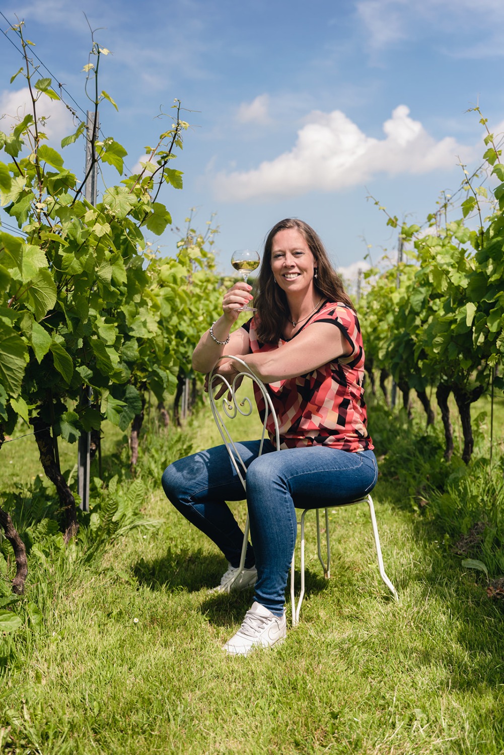 Margret Weijers zit met een glas wijn in de wijngaard
